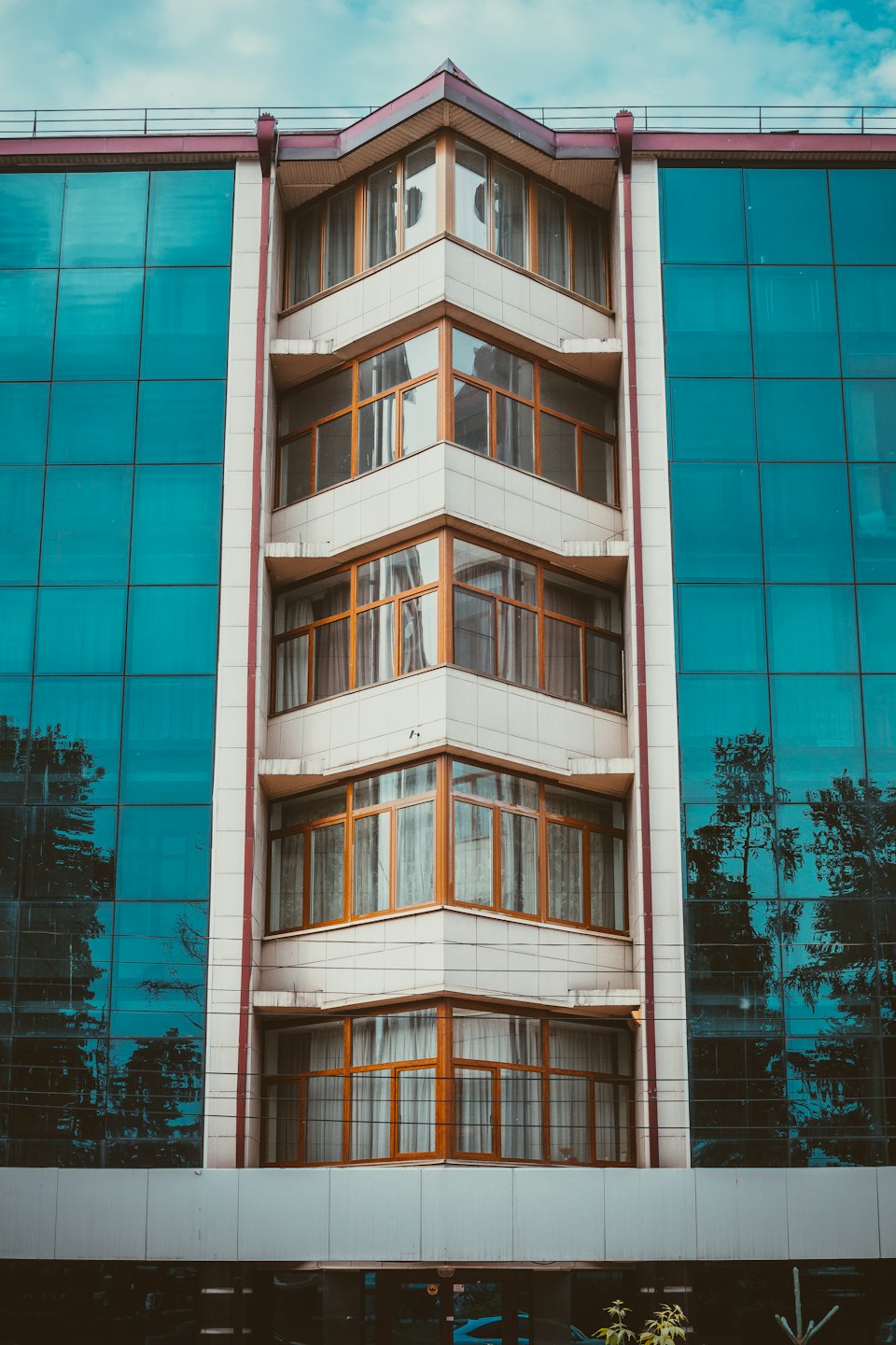 Modern gebouw met houten kozijnen en blauwe glaspanelen.